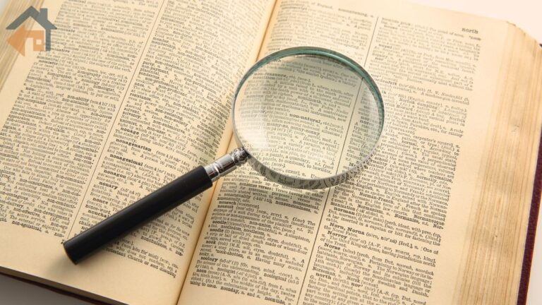 A magnifying glass resting on open dictionary pages, representing HECM terms explained in plain language for REALTORS
