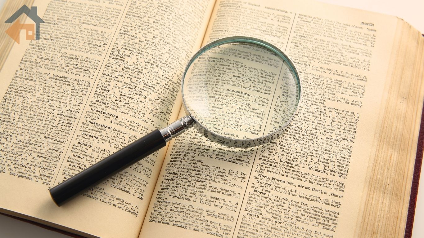 A magnifying glass resting on open dictionary pages, representing HECM terms explained in plain language for REALTORS